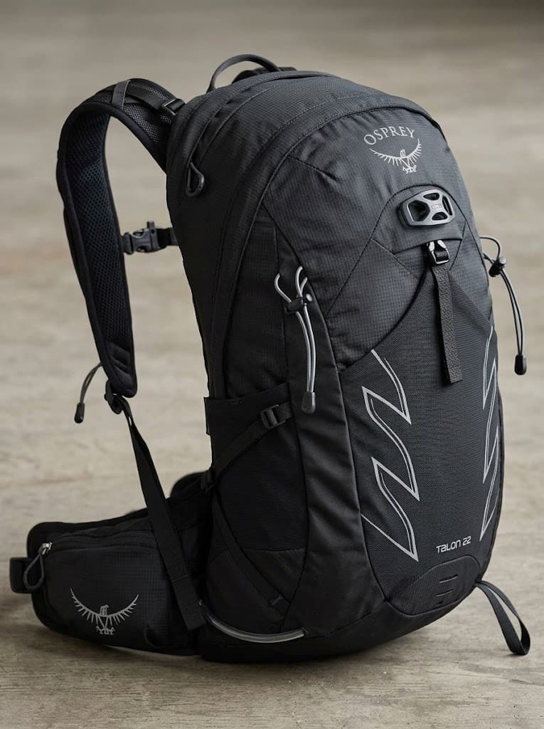 A black Osprey backpack marked Talon 22, with a front stretch pocket and hip belt.